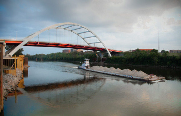 The Cumberland River at Nashville, an Ingram tow boat pushes a barge loaded with sand upriver under the Korean War Veterans Memorial Bridge